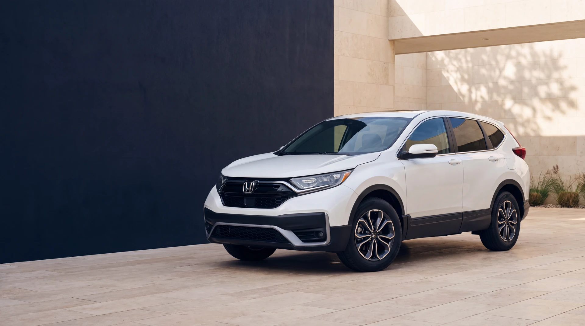 White Honda CR-V in a warm-stone courtyard beside a deep blue architectural wall