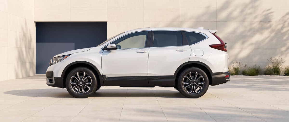 Side profile of the white 2022 Honda CR-V in a warm-stone architectural setting