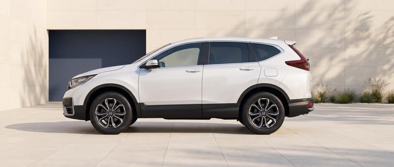 Side profile of the white 2022 Honda CR-V in a warm-stone architectural setting