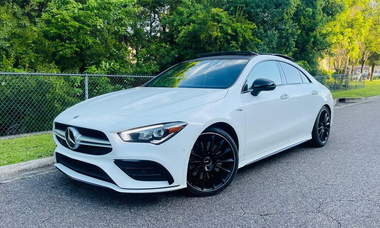 White Mercedes-Benz CLA coupe, front three-quarter view at dusk