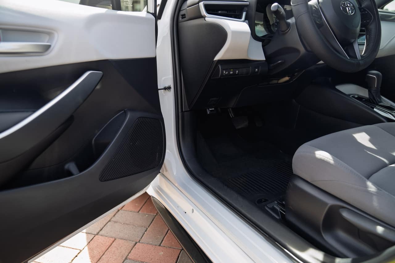 Toyota Corolla driver footwell, seat controls, and open front door