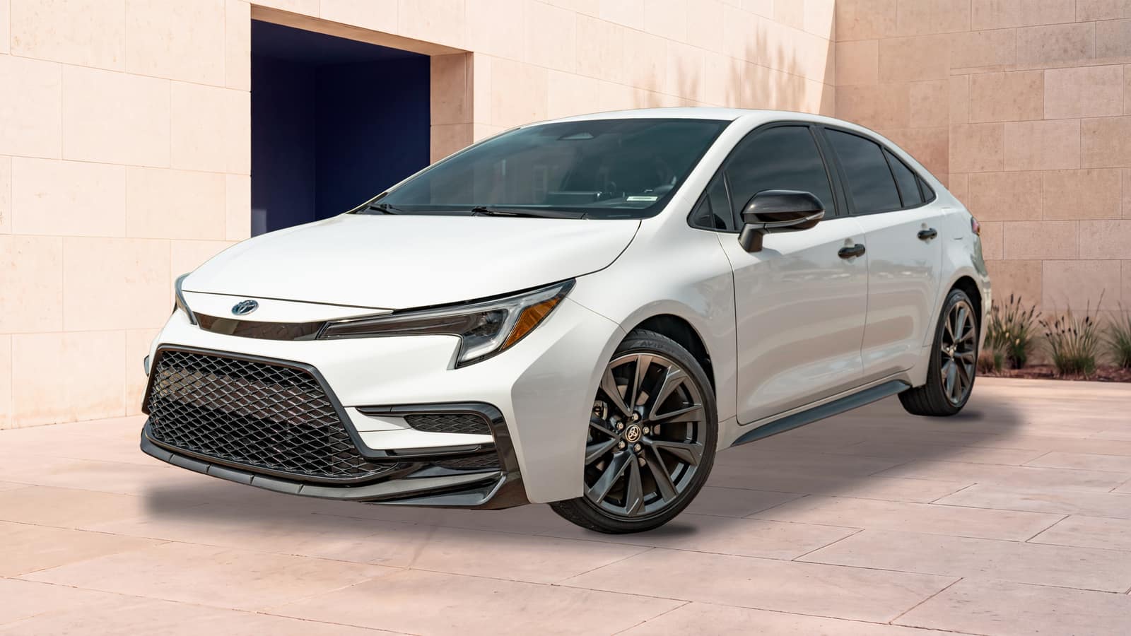 White 2023 Toyota Corolla Hybrid SE, front three-quarter view in an architectural courtyard